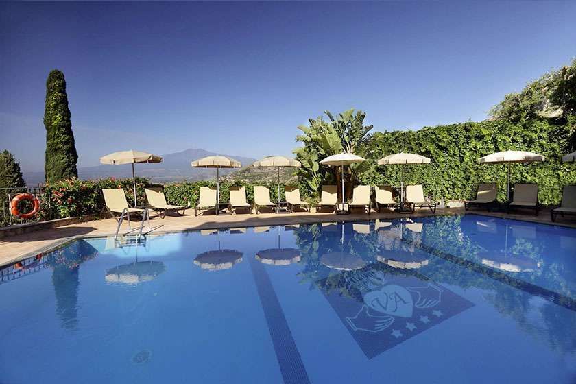 A large swimming pool surrounded by chairs and umbrellas.