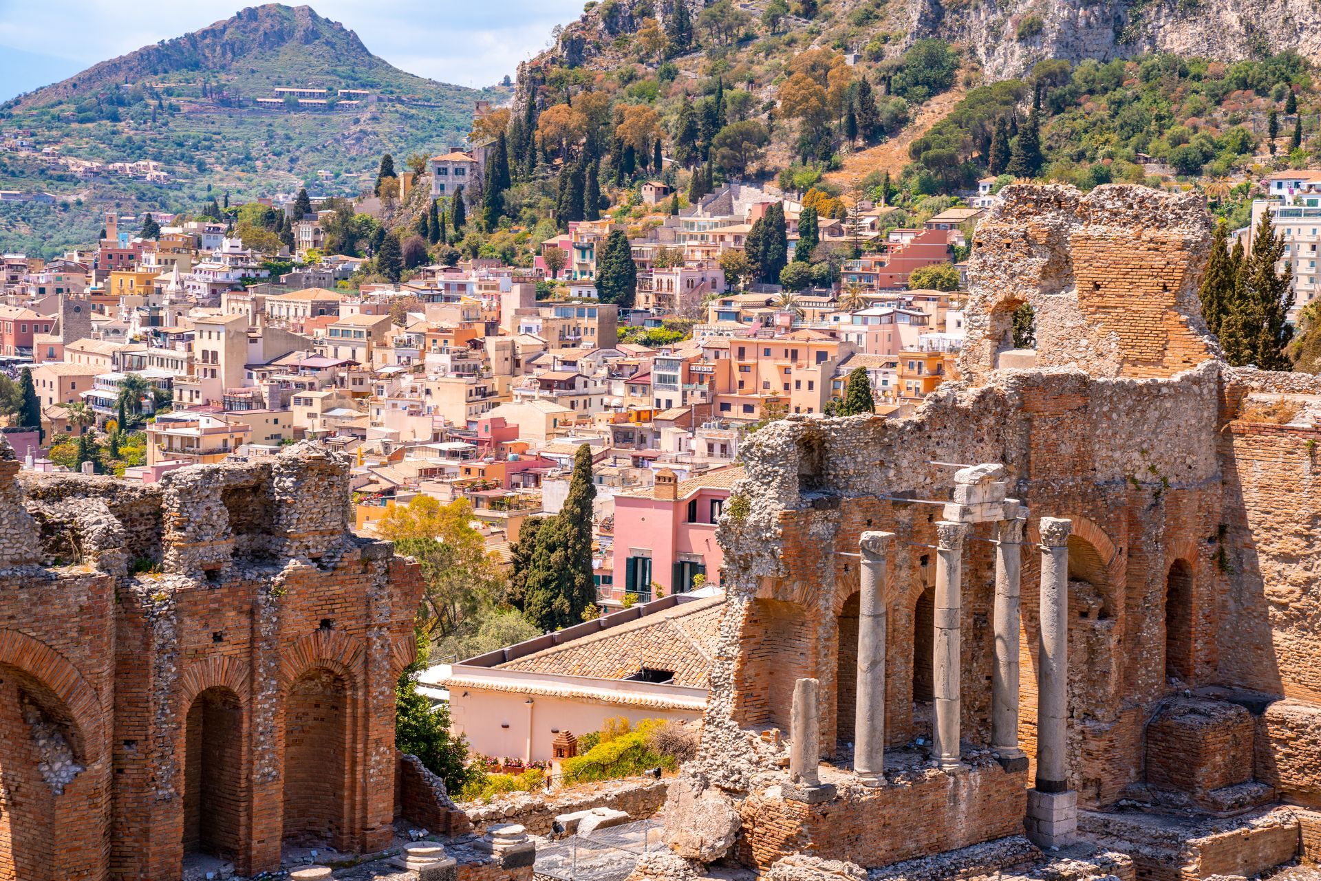 A city with a mountain in the background and a ruined building in the foreground.