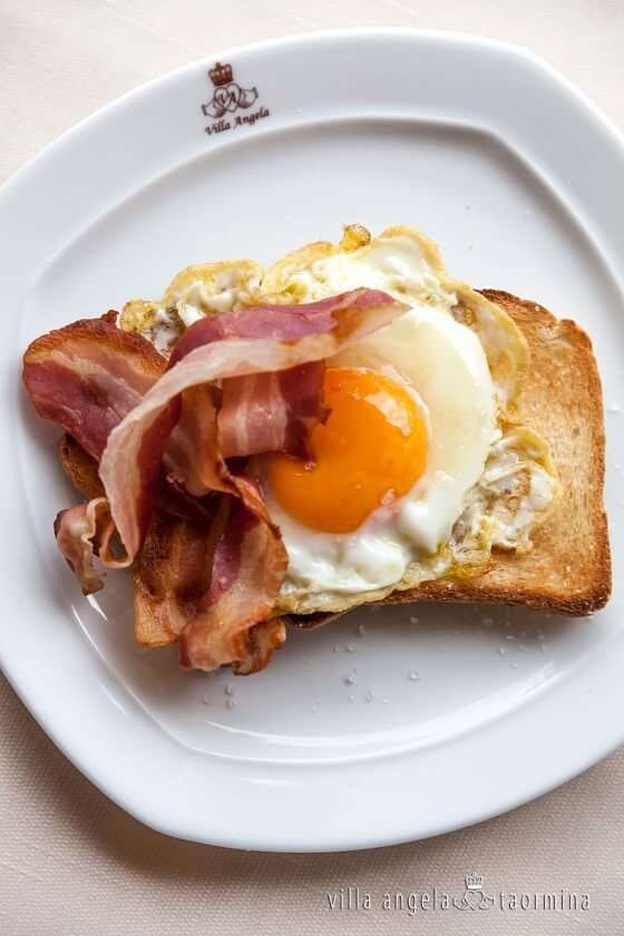 A white plate with a fried egg and bacon on it