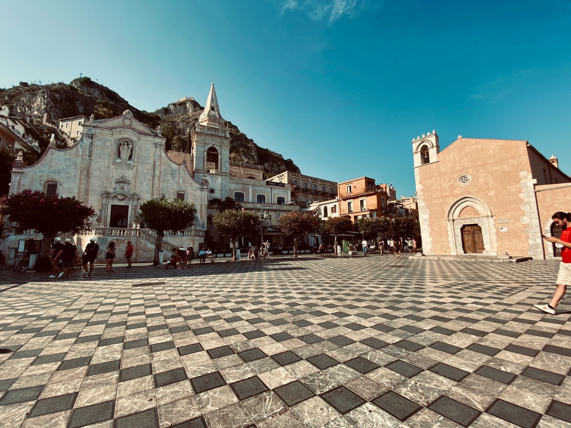 A man is walking in a square in front of a church.