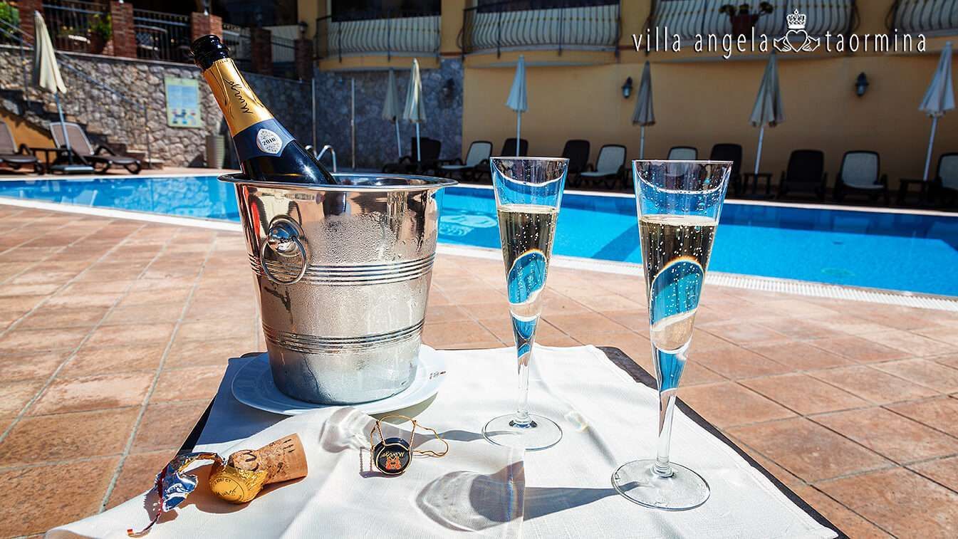 A bucket of champagne sits on a table next to two glasses of champagne