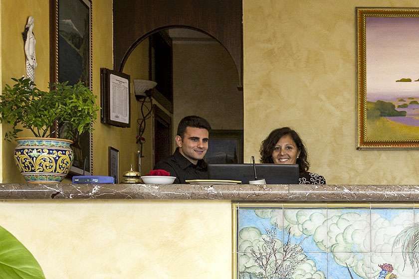 A man and a woman are sitting at a hotel reception desk.