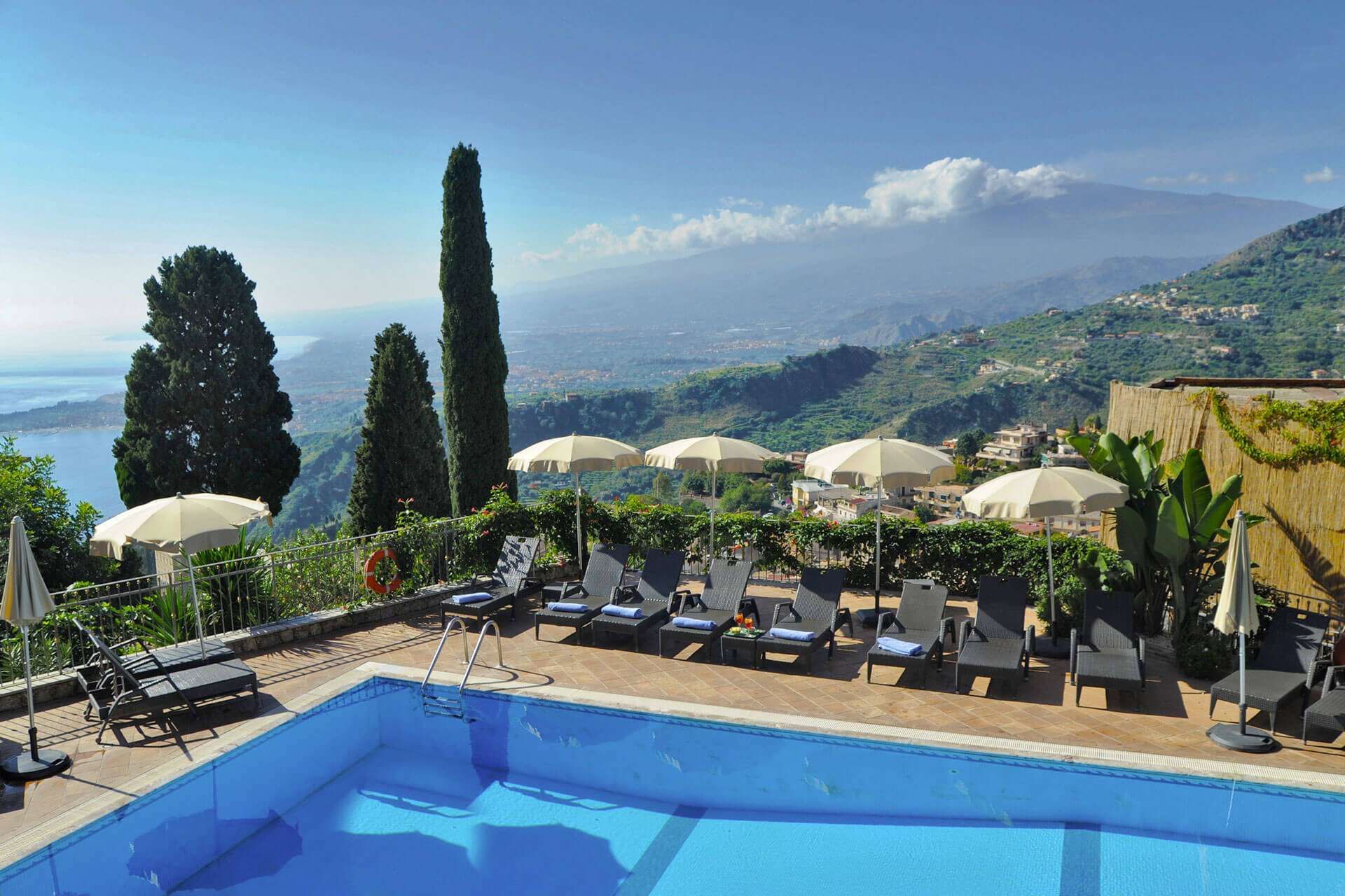 Ein großer Swimmingpool mit Stühlen und Sonnenschirmen drumherum