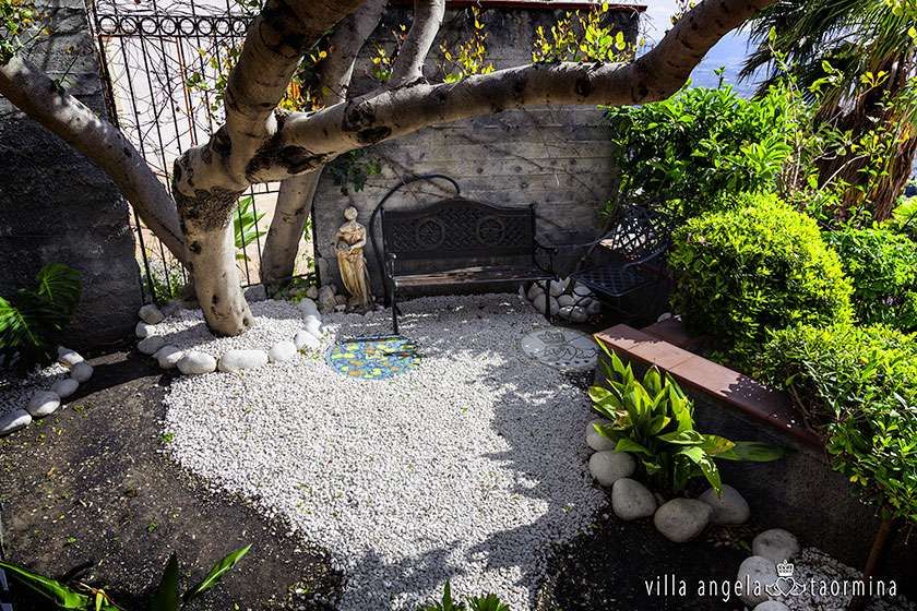 Ein Garten mit einer Bank unter einem Baum und einer Statue