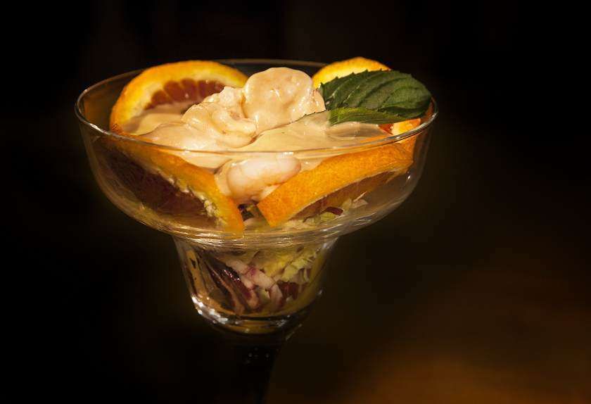 Eine Glasschüssel mit Salat und Obst auf einem Tisch.