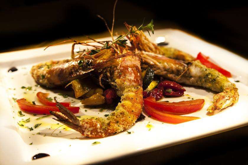 A white plate topped with shrimp and vegetables on a table.