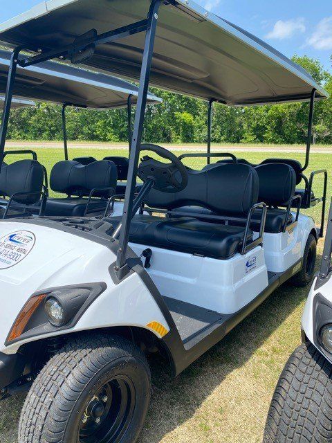 A white golf cart with black seats is parked on the grass