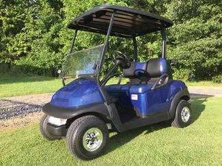 A blue golf cart is parked on a lush green field.