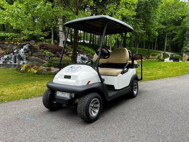 A white golf cart is parked on the side of a road.