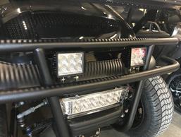 A golf cart with a bumper and lights on it is parked in a garage.