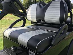 A black and white striped golf cart seat with a steering wheel.