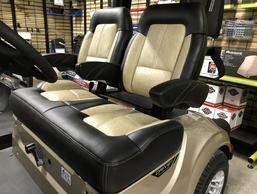 The seats on a golf cart are black and tan.