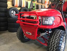 A red golf cart is parked in front of a stack of tires.