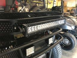 A row of golf carts are parked next to each other in a garage.