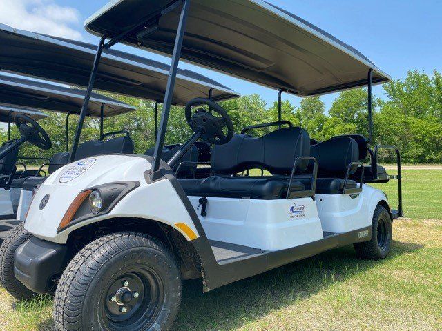 A white golf cart is parked in a grassy field.