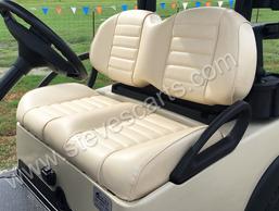 A golf cart with white seats and a steering wheel is parked in a grassy field.