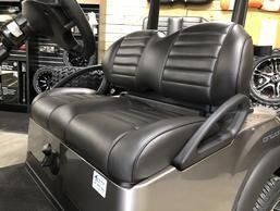 A golf cart with a black leather seat is sitting in a store.