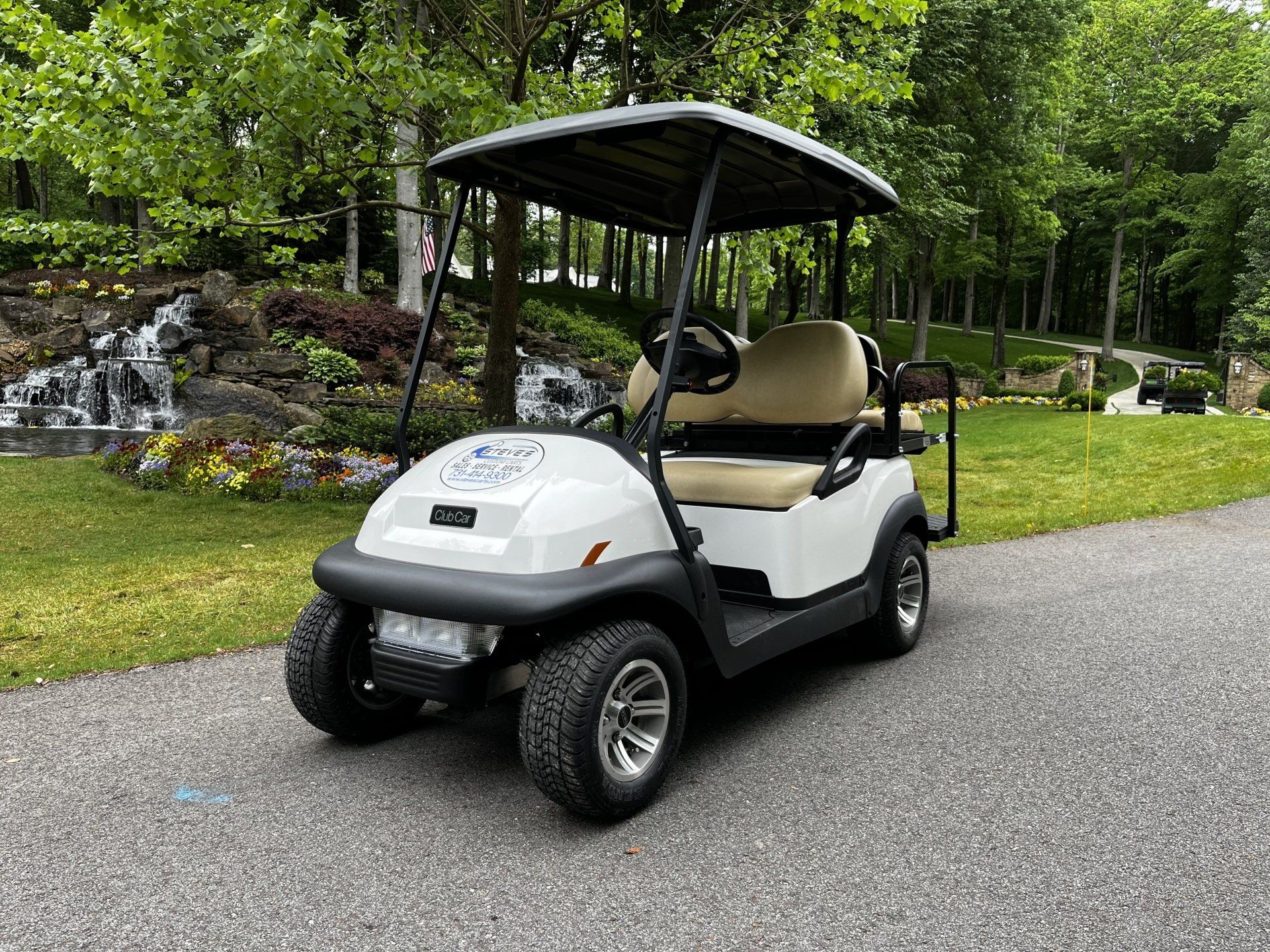 A white golf cart is parked on the side of a road.