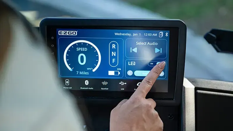 Person taps a blue car dashboard touchscreen showing speed and navigation controls