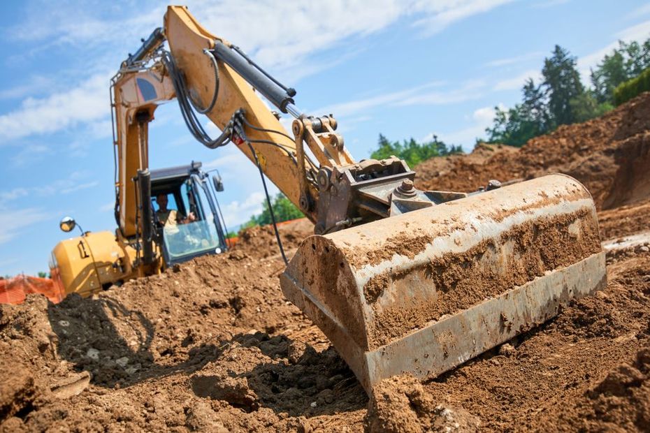 Yellow excavator digging soil on a construction site under a blue sky