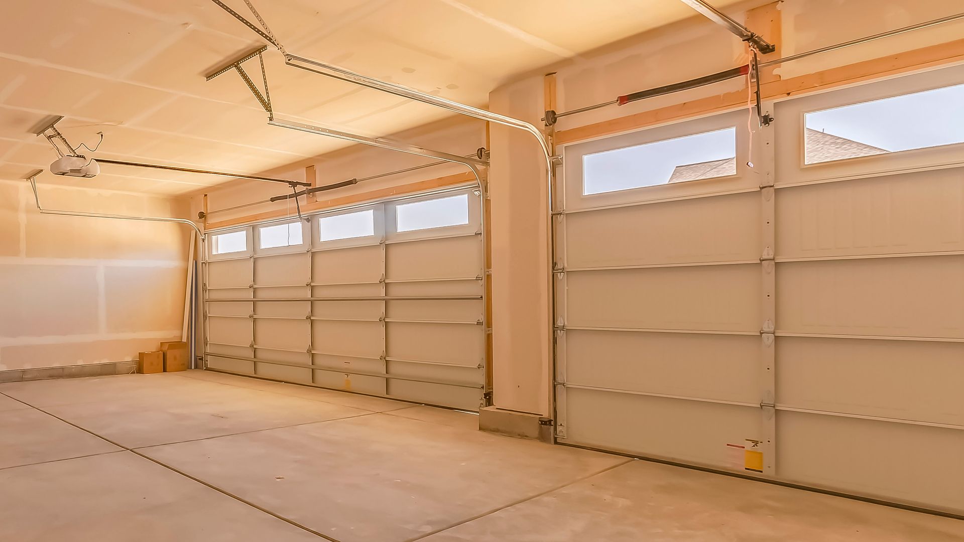 Spacious empty garage interior with two sectional overhead doors and natural light.