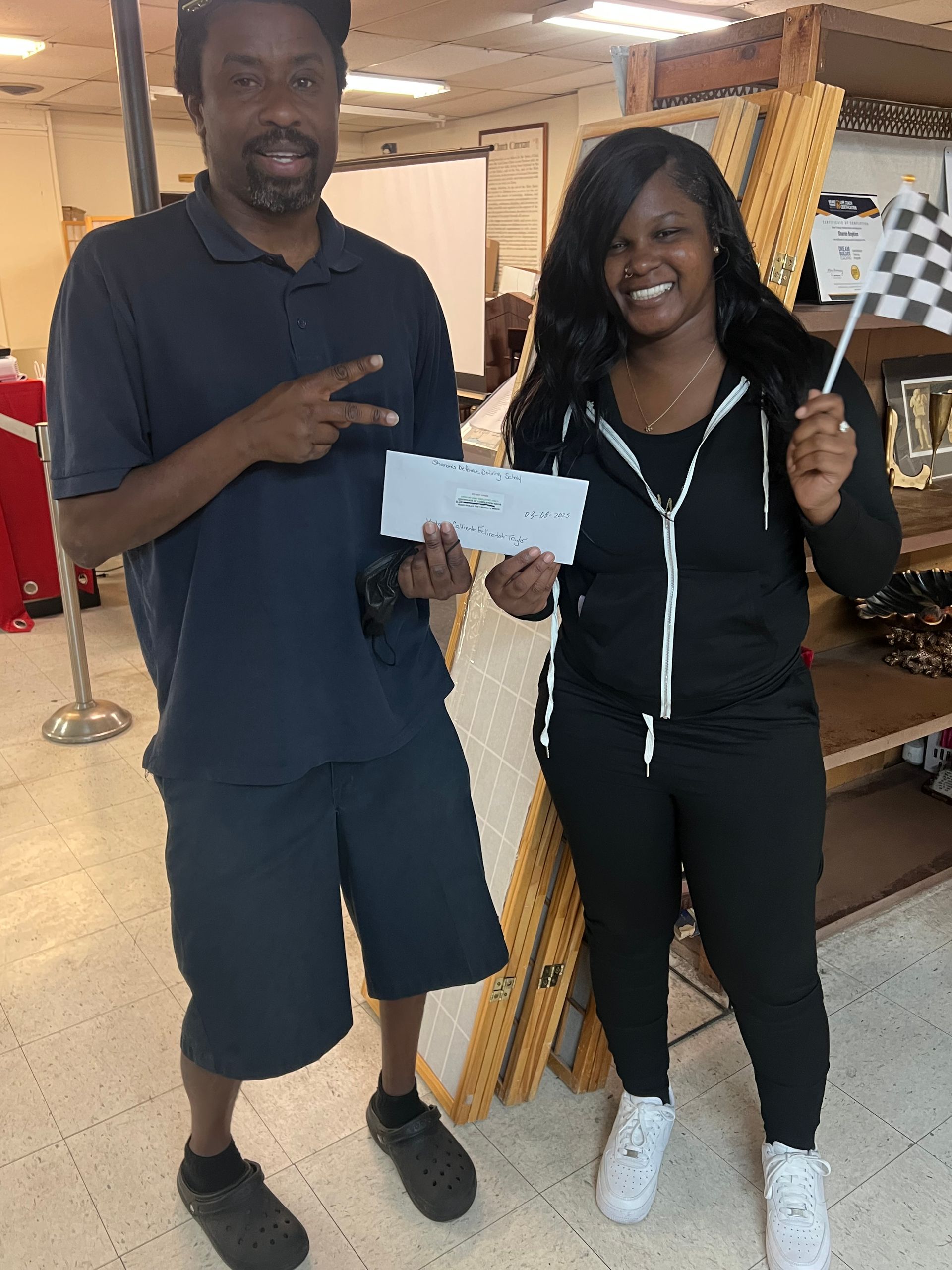 A man and a woman are standing next to each other in a store holding a check and a checkered flag.