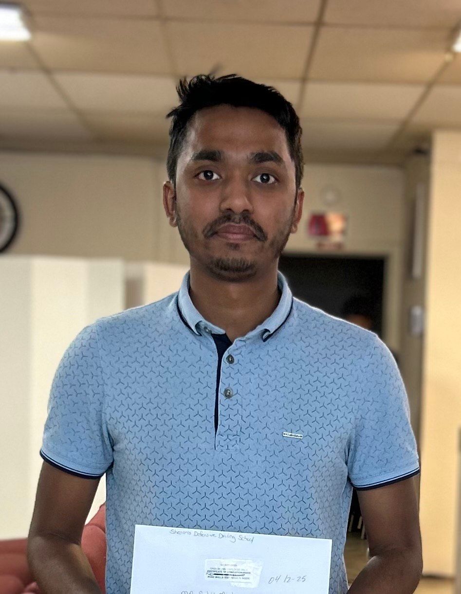 Man in blue polo shirt holding a document, in a room with light-colored walls.