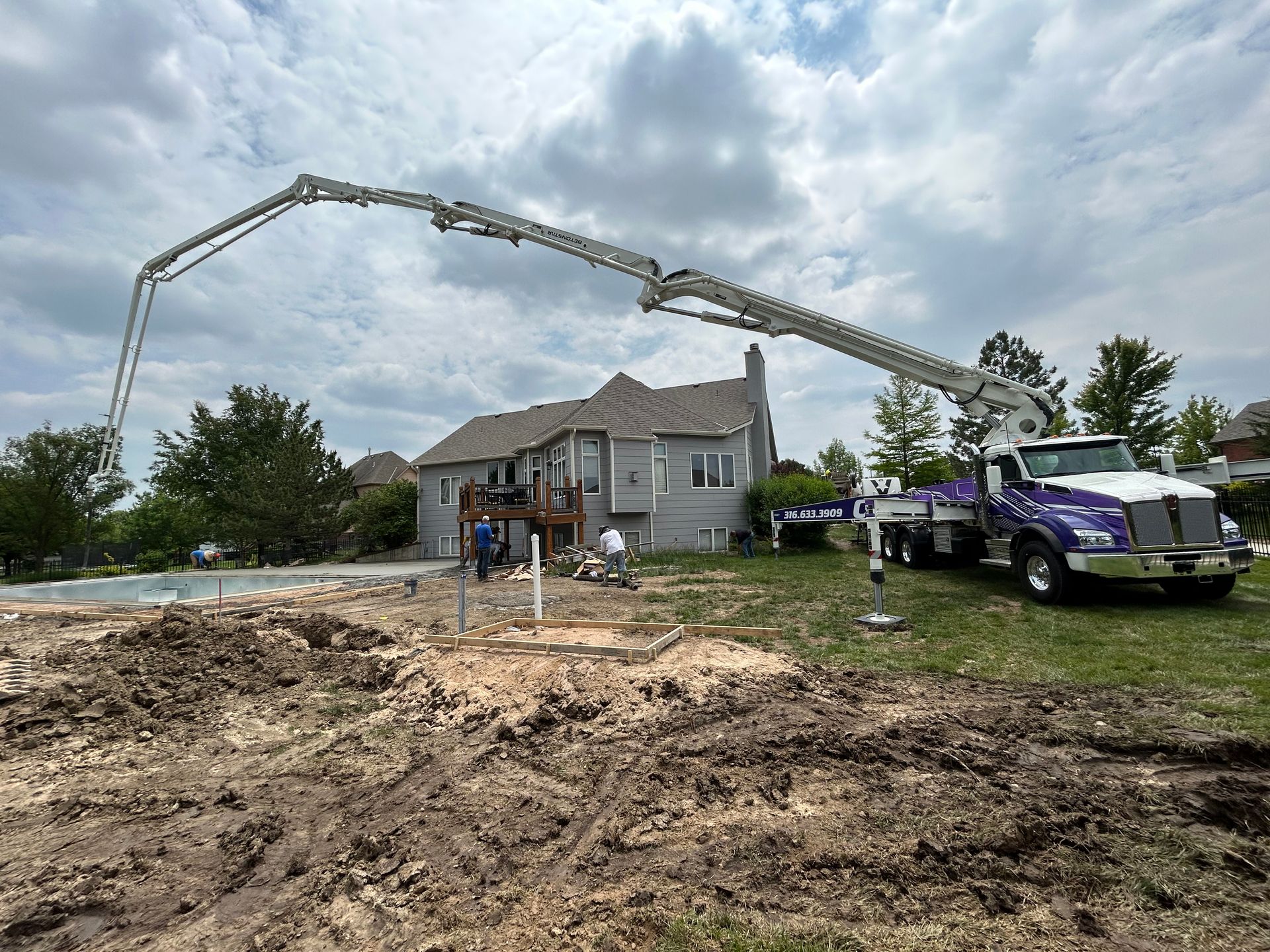 A purple truck is pumping concrete in front of a house.