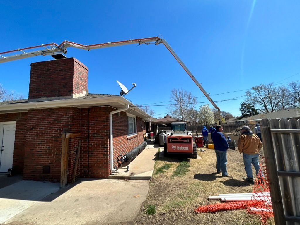 A crane is being used to pour concrete into a brick house