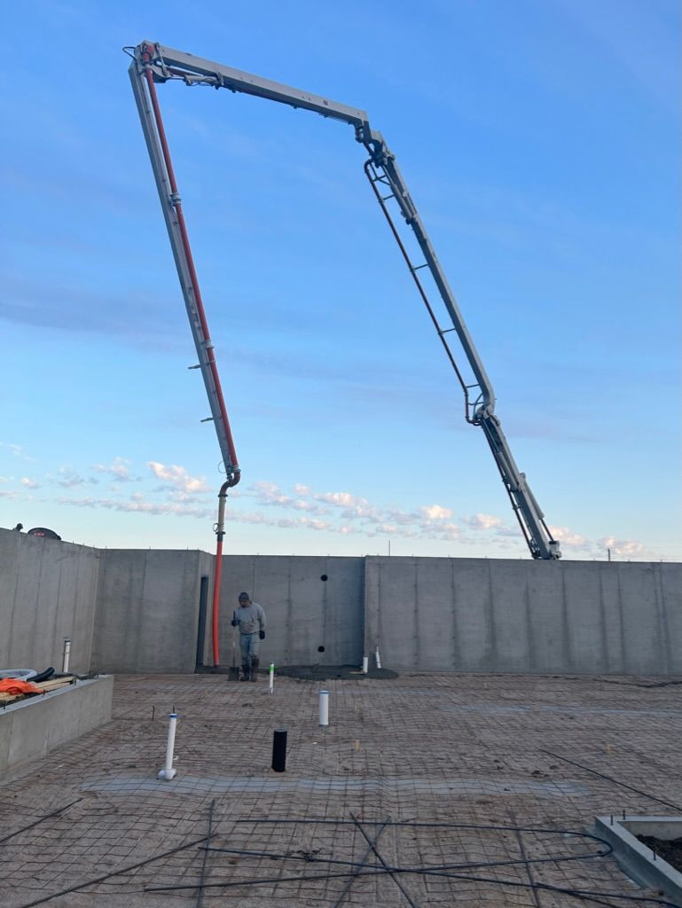 A man is standing in front of a concrete pump on a construction site.