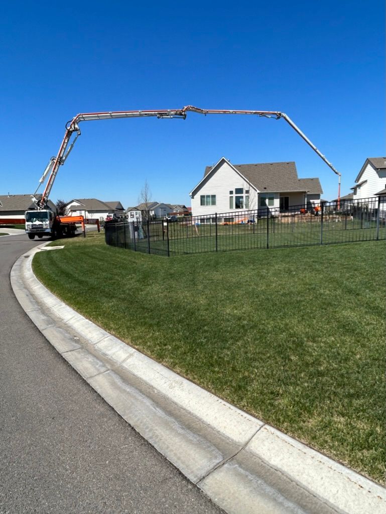 A concrete pump is being used to pour concrete into a yard.