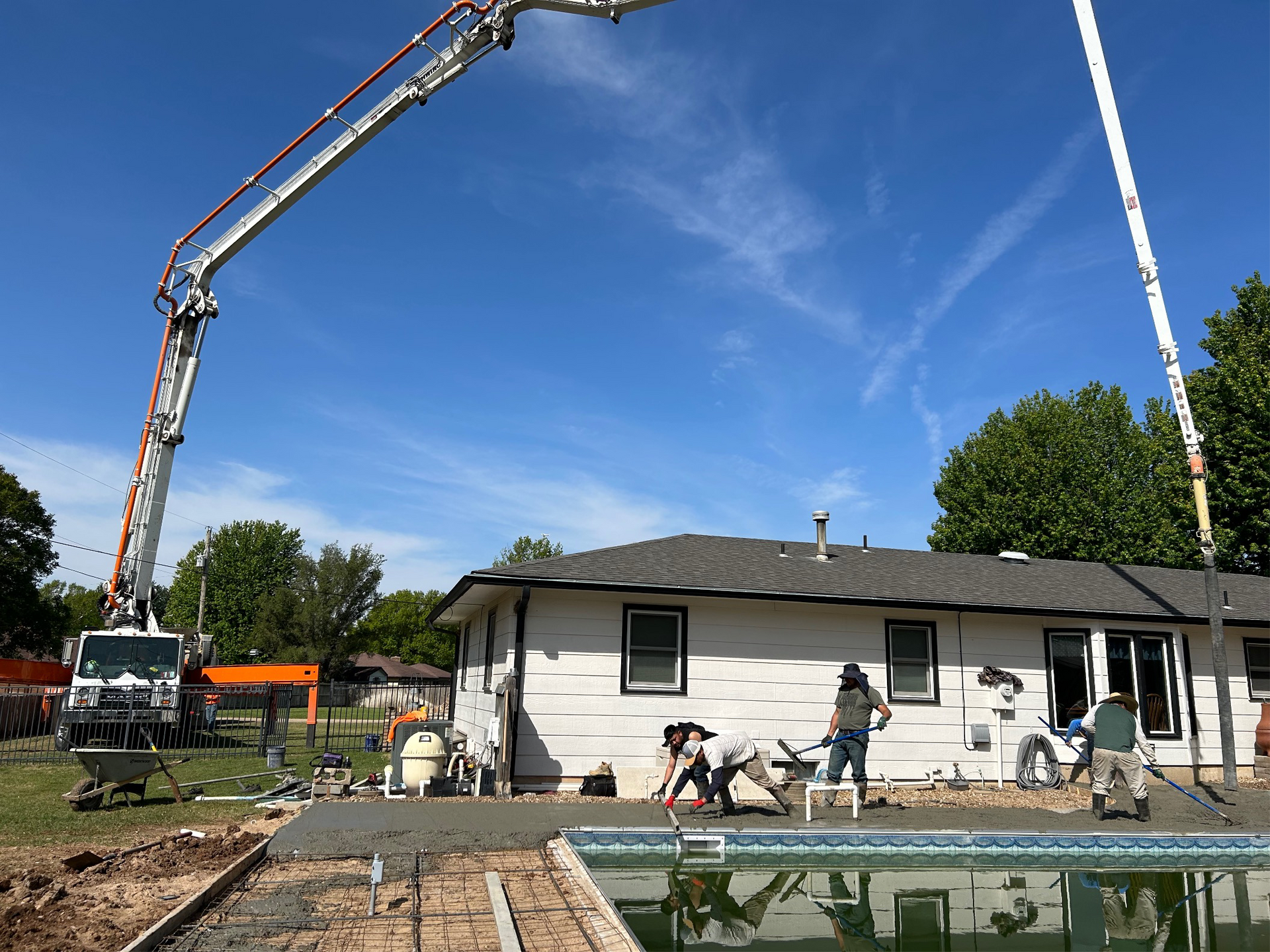 A concrete pump is being used to pour concrete in front of a house.