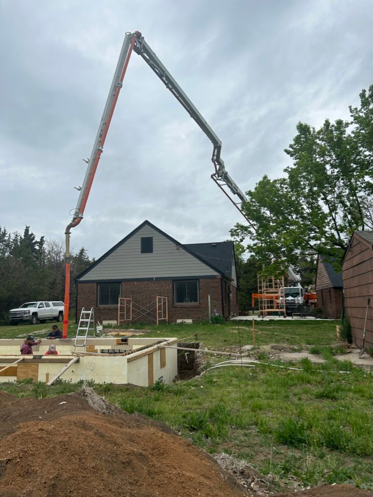 A concrete pump is being used to pour concrete in front of a house.