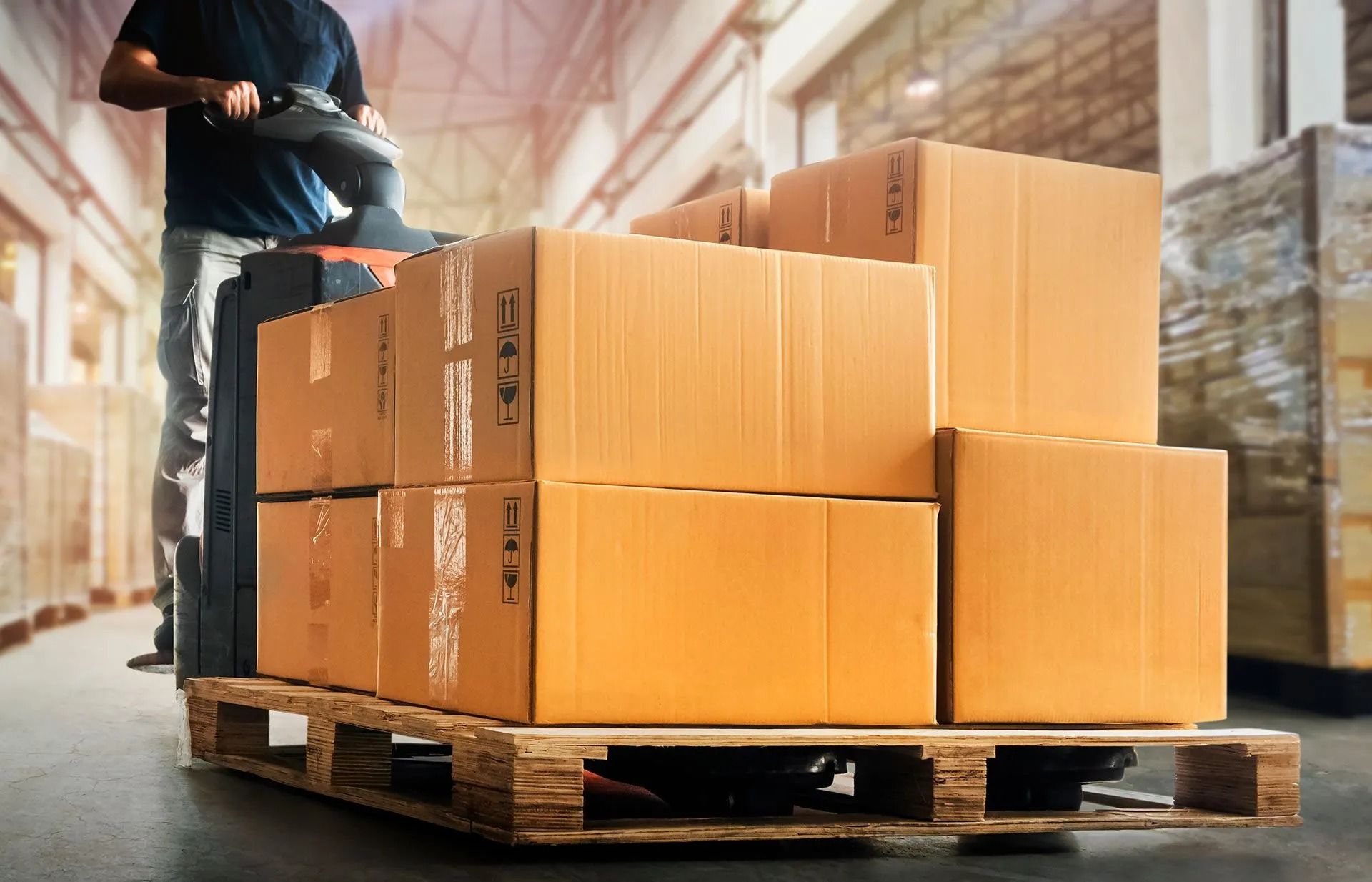 Worker stacking cardboard boxes on a pallet in a warehouse