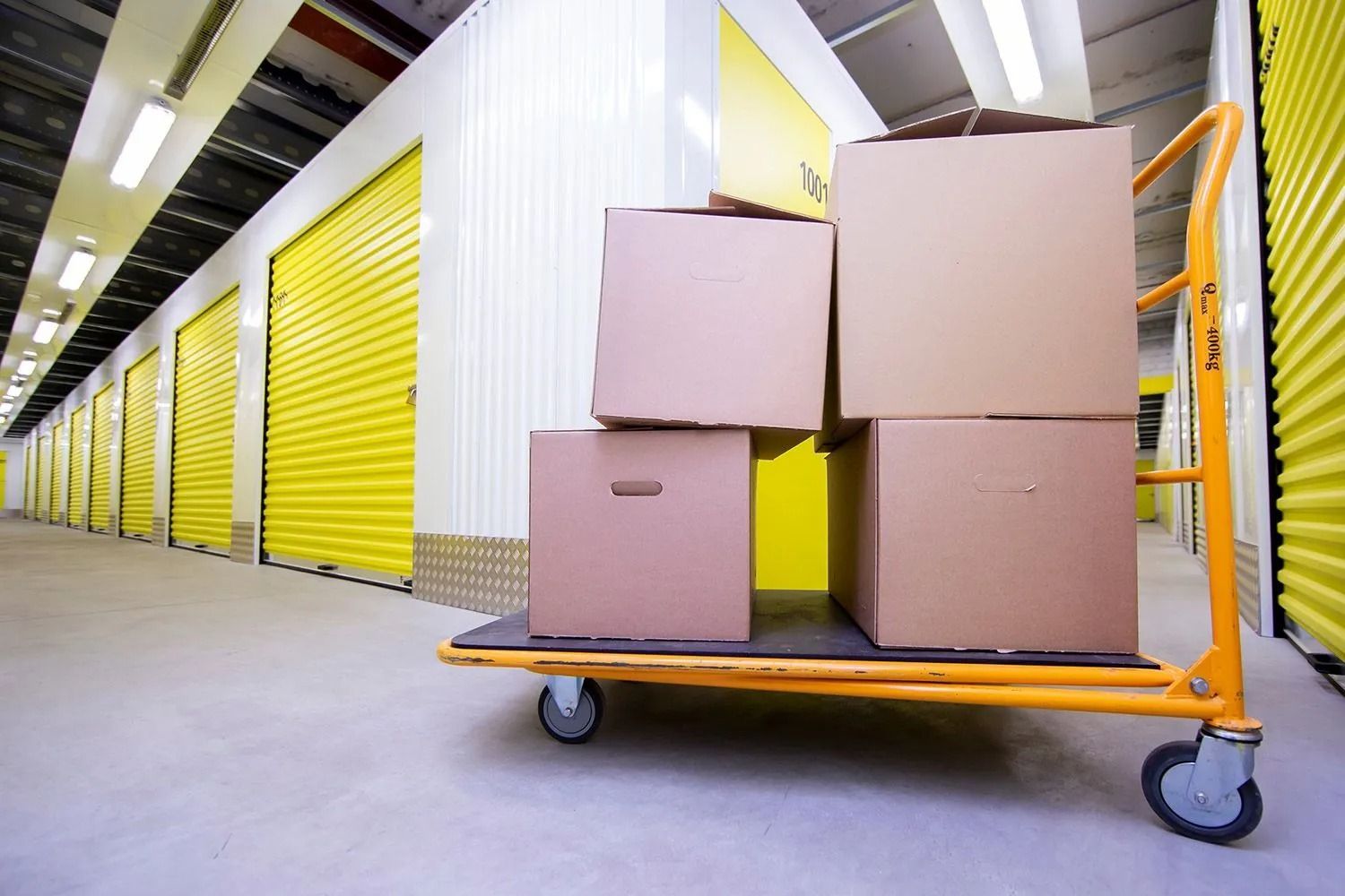 Boxes stacked on a yellow cart in a warehouse aisle with yellow storage doors