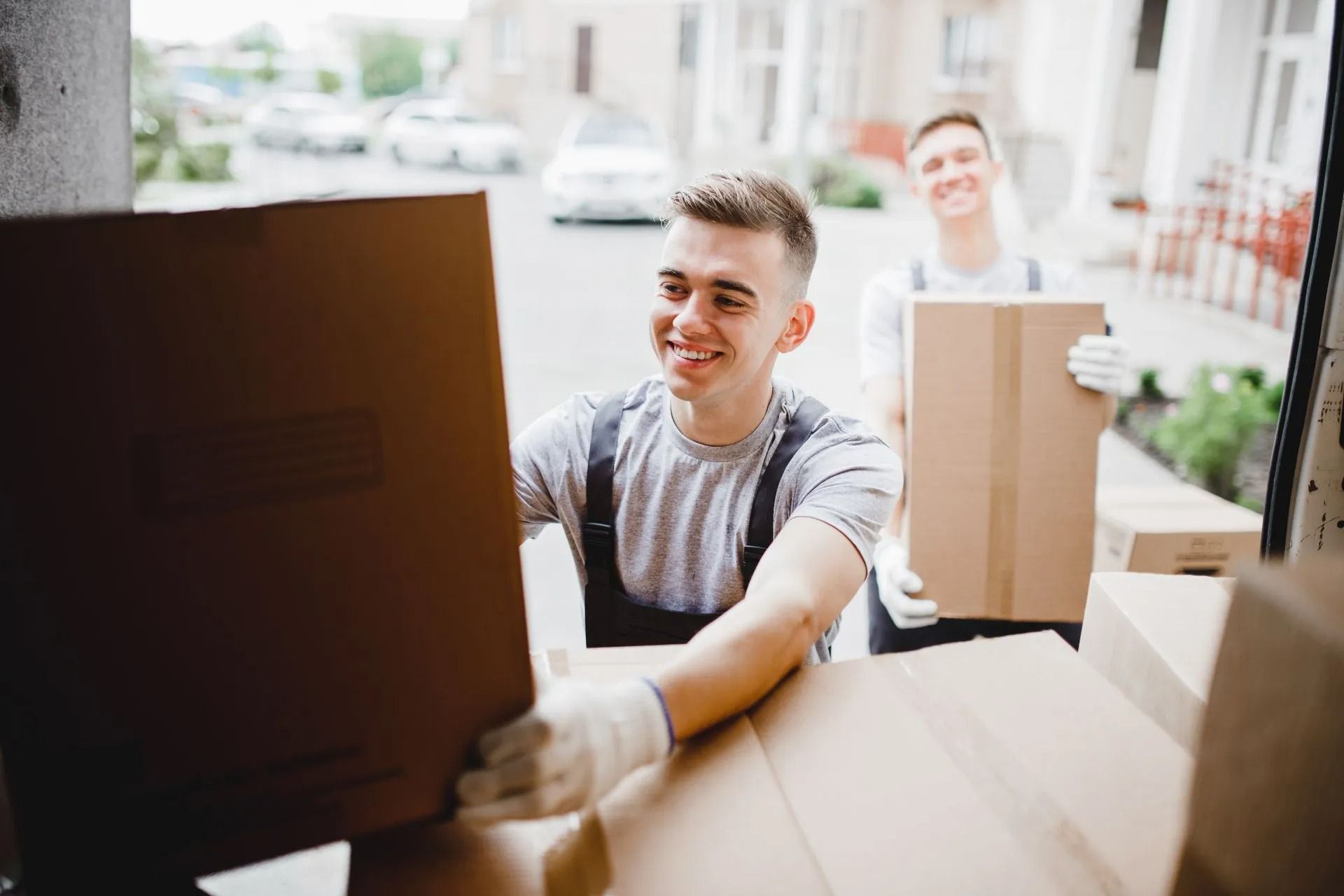 Delivery workers loading boxes onto a van in a sunny street