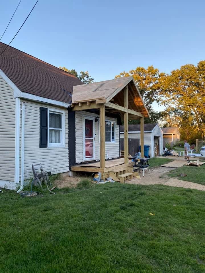 House exterior with a new front porch under construction, white siding, and a red front door