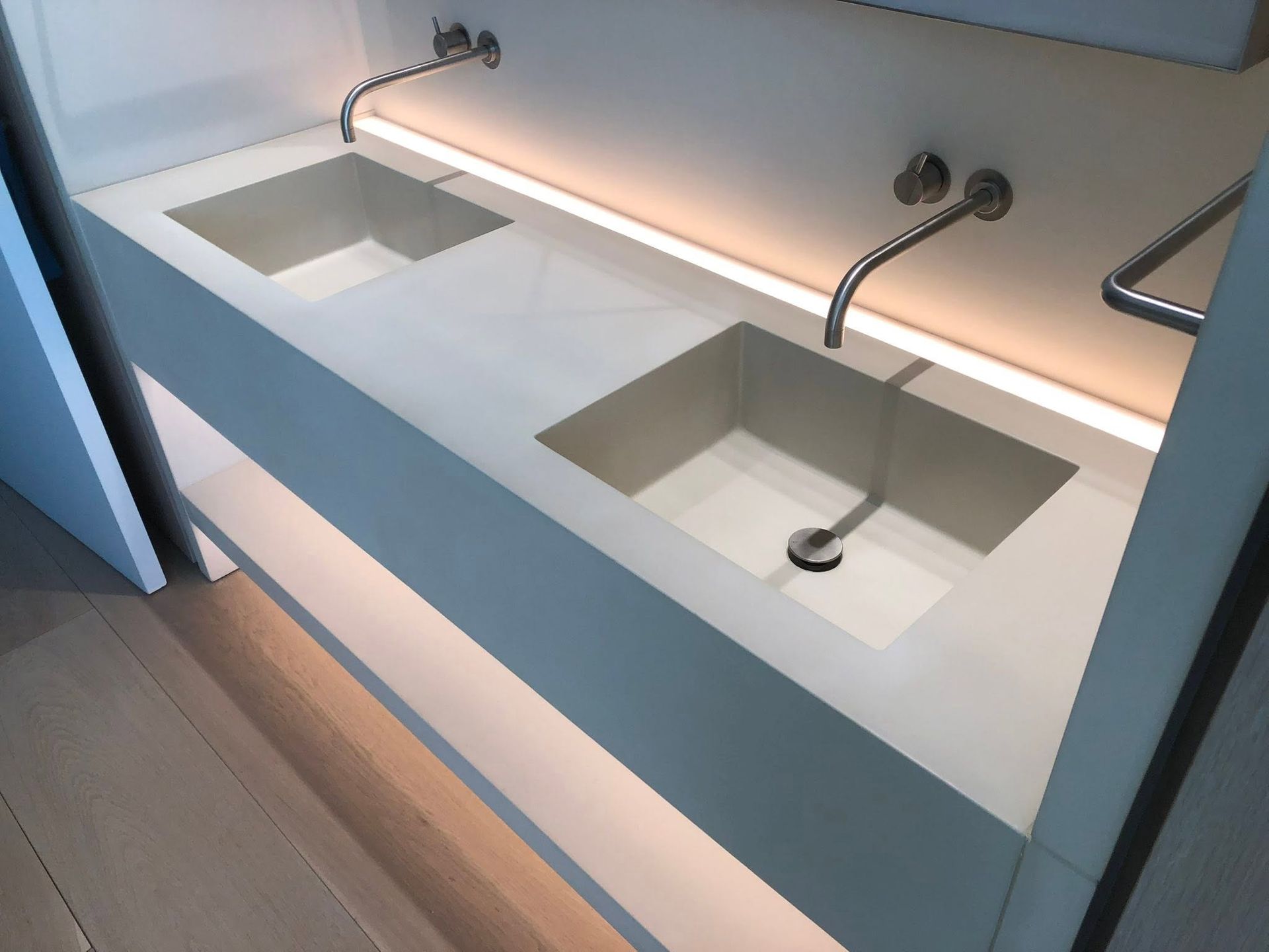 Modern bathroom counter with two built-in sinks and chrome faucets under warm under-cabinet lighting
