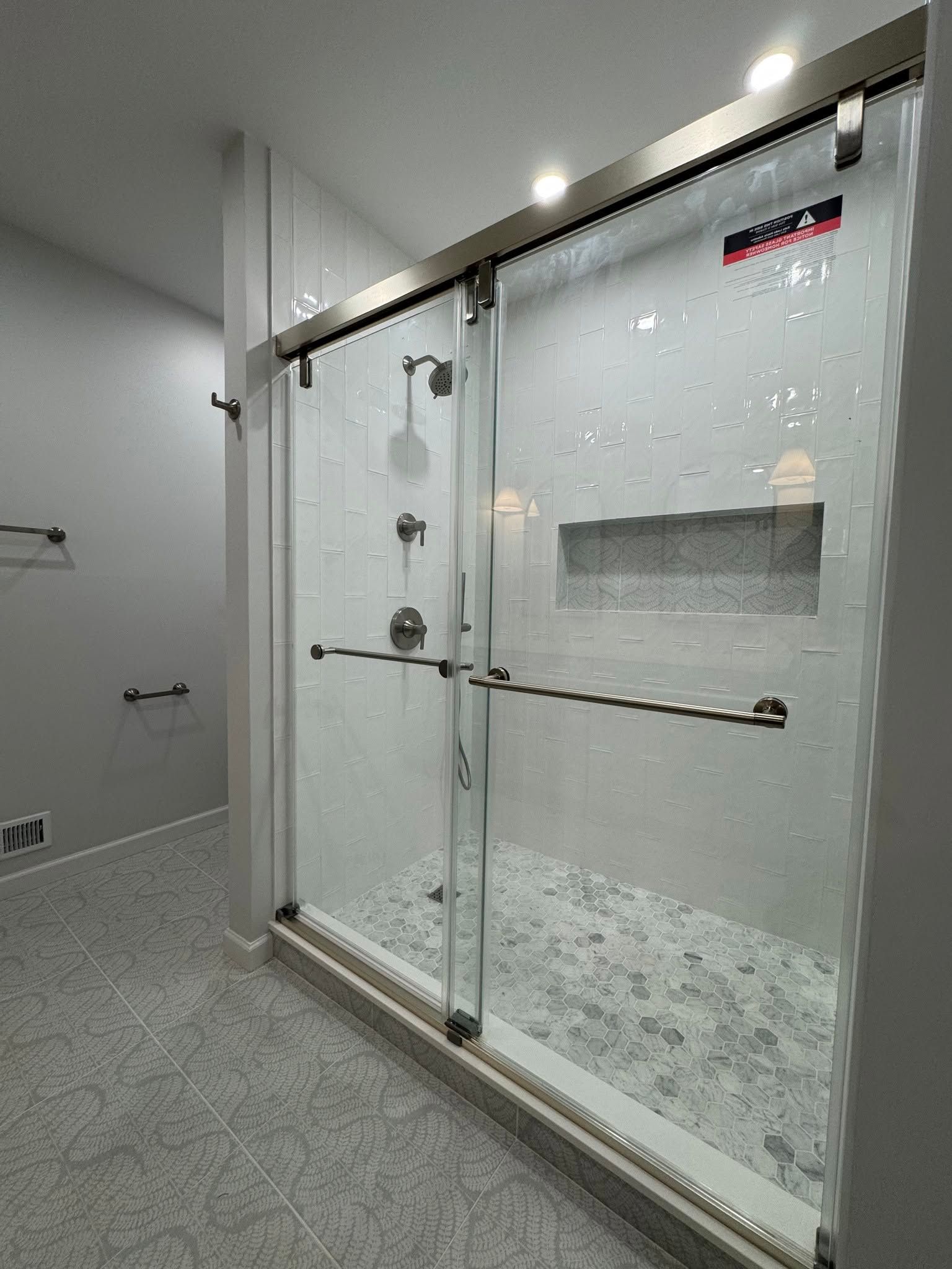 Glass shower enclosure with frosted doors and chrome hardware in a modern bathroom