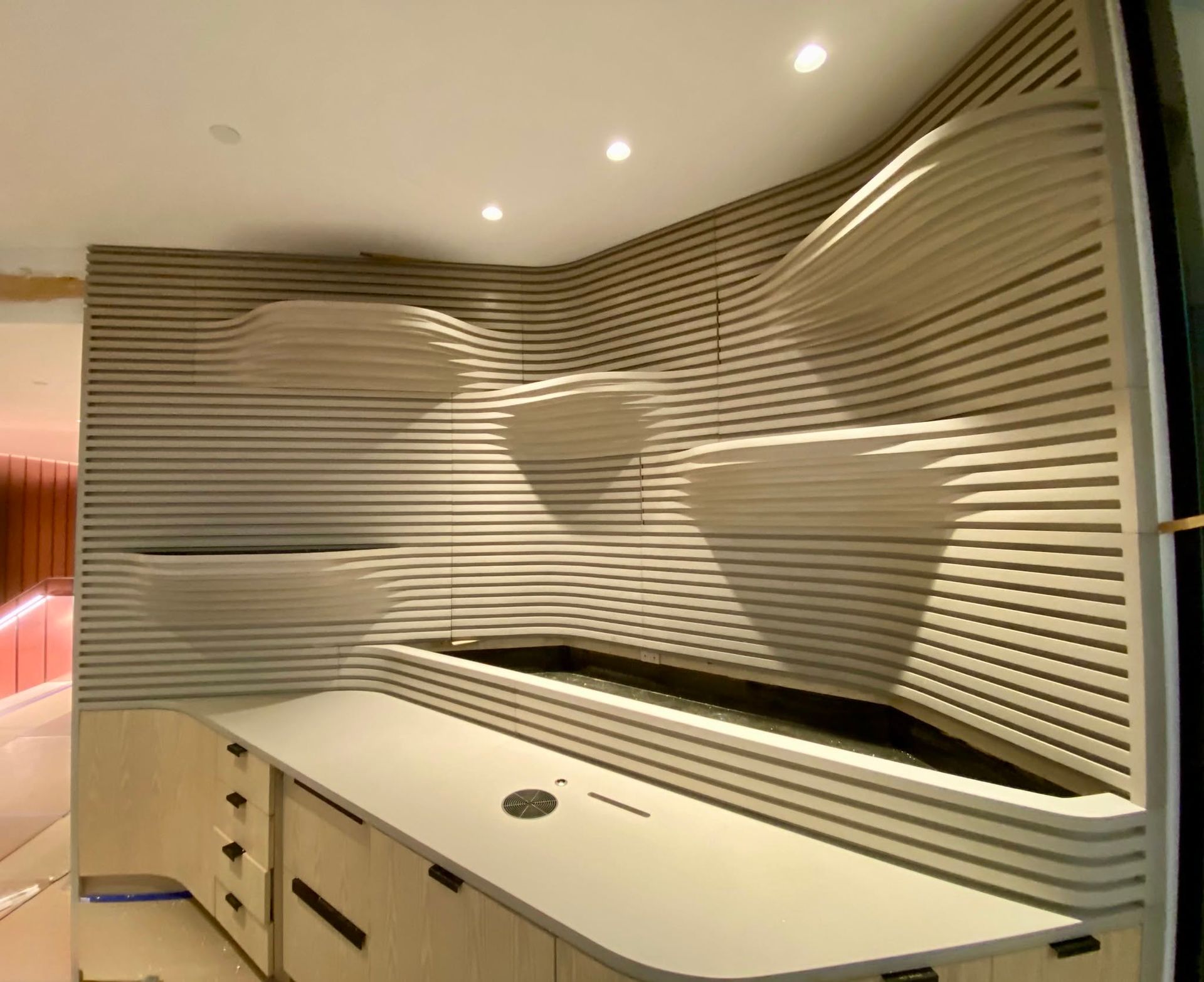 Modern white reception desk with wavy wall panels and recessed ceiling lights