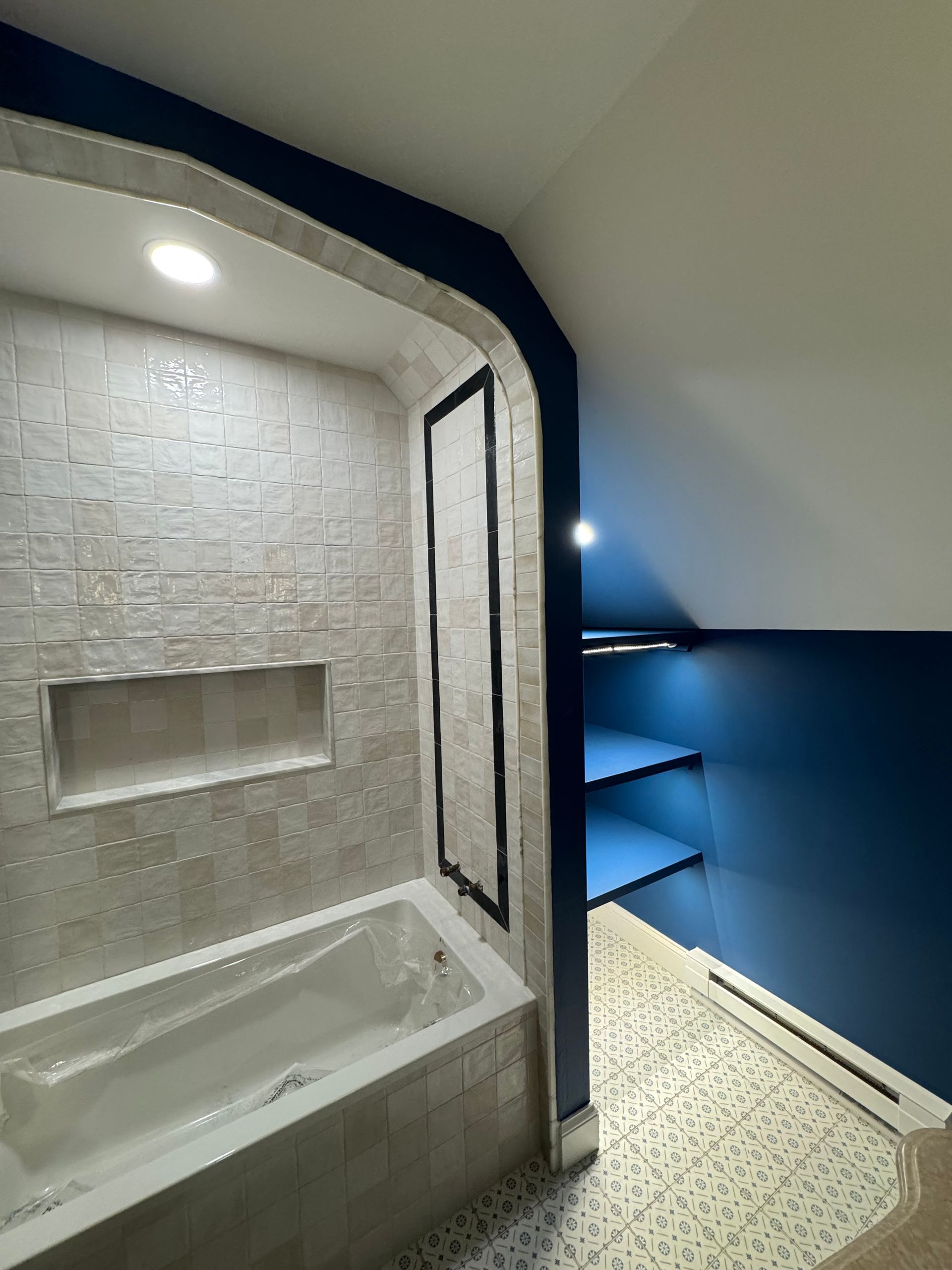 Bathroom with tiled shower tub, arched opening, and blue walls in a corner space