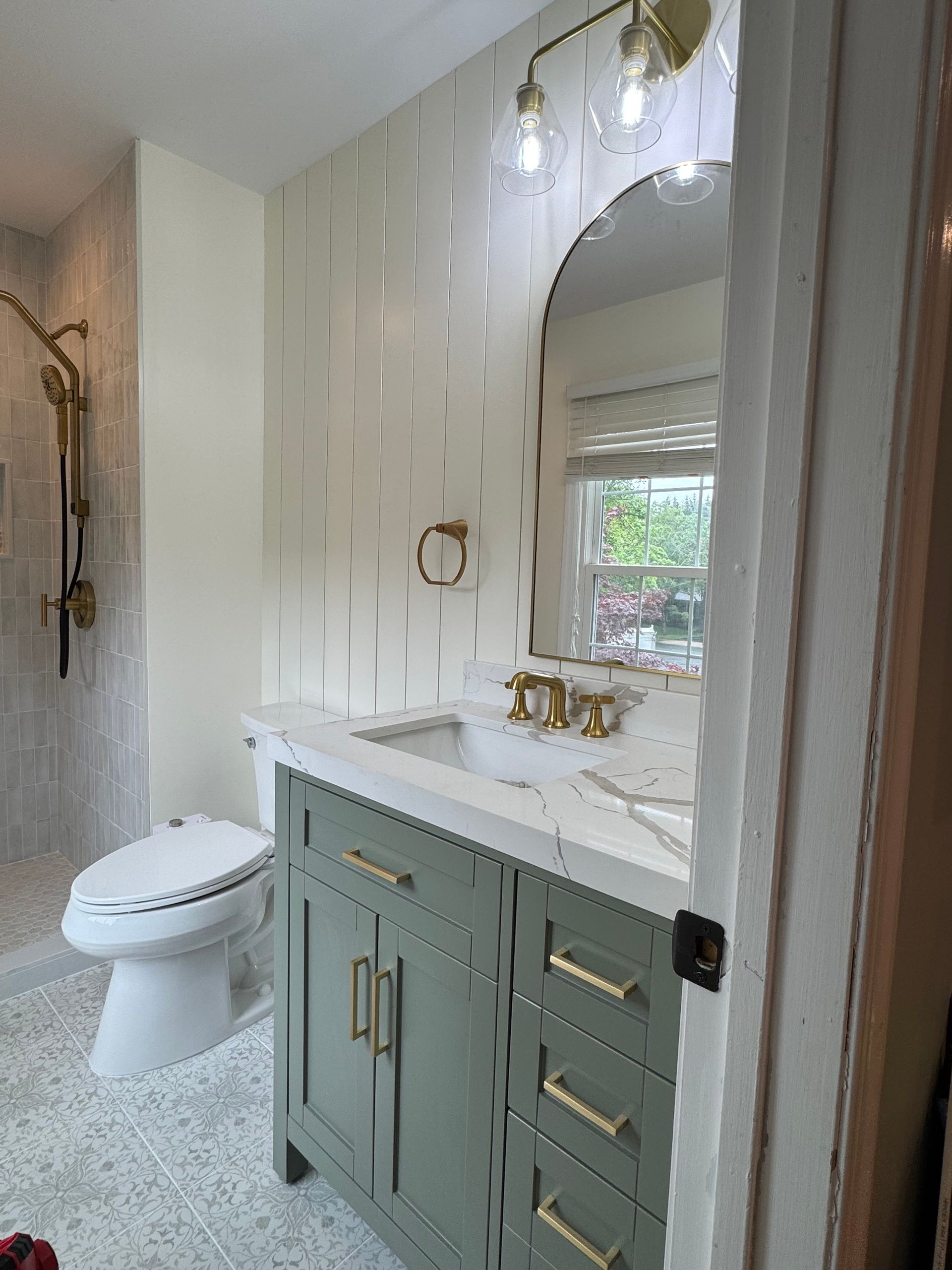 Modern bathroom with a double vanity, round mirror, toilet, and white patterned walls