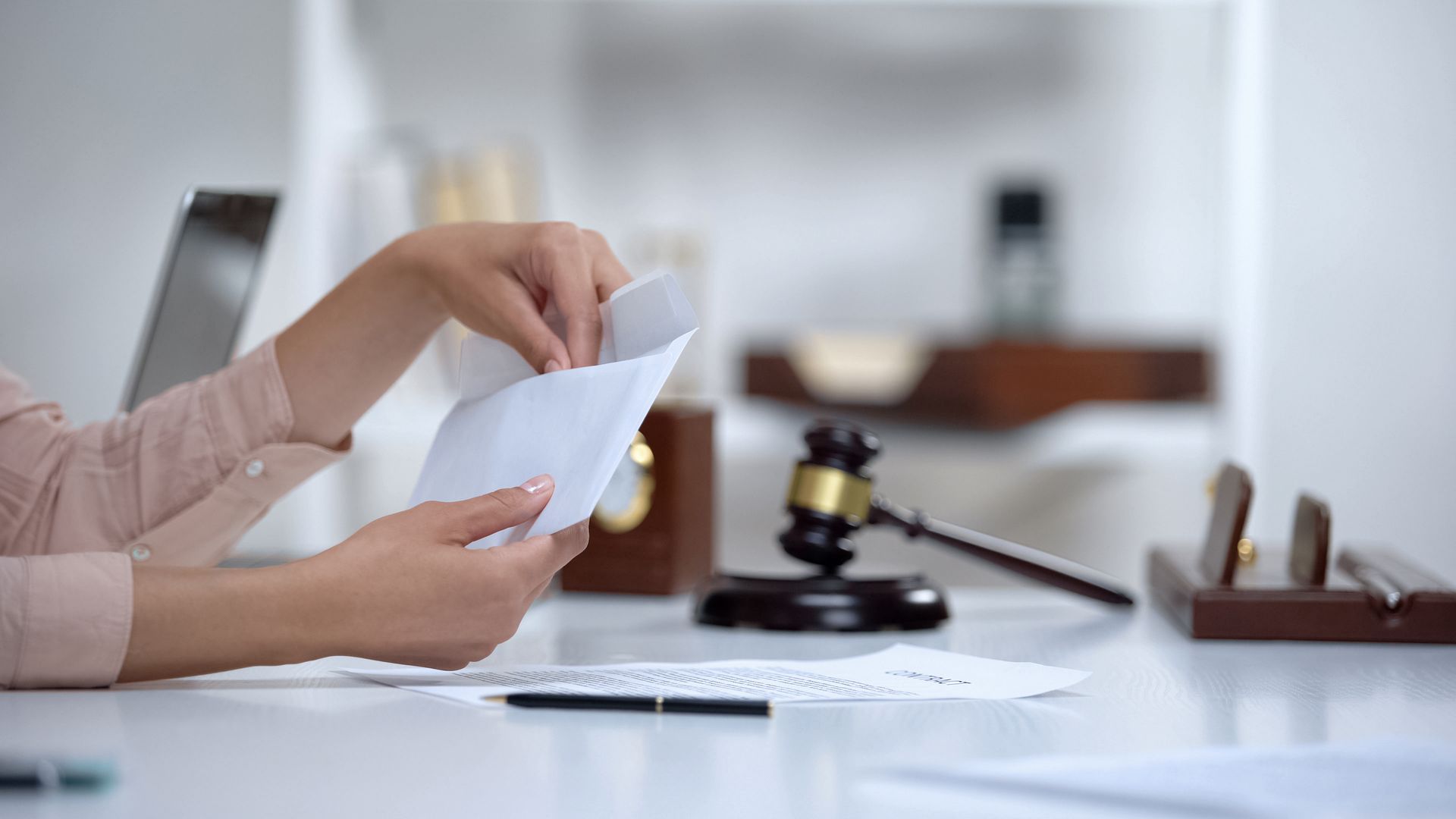 A woman is holding a piece of paper in front of a judge 's gavel.