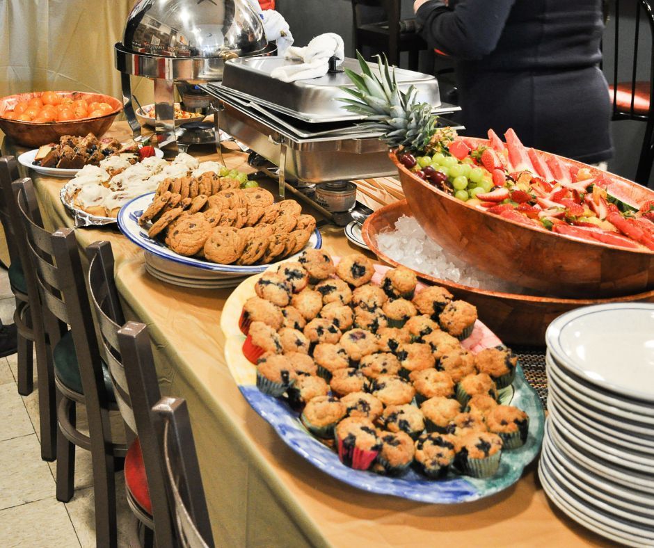 A buffet table with a variety of food including cookies and muffins