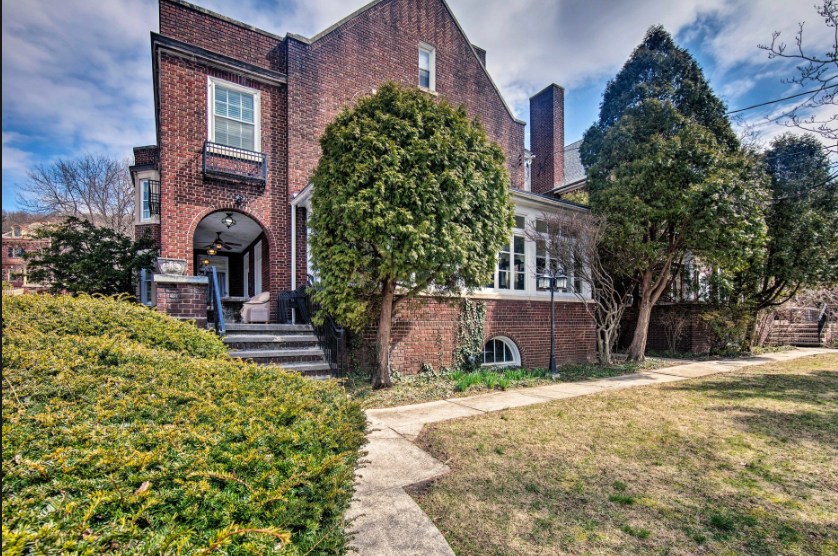 A large brick house with a lot of windows and trees in front of it.