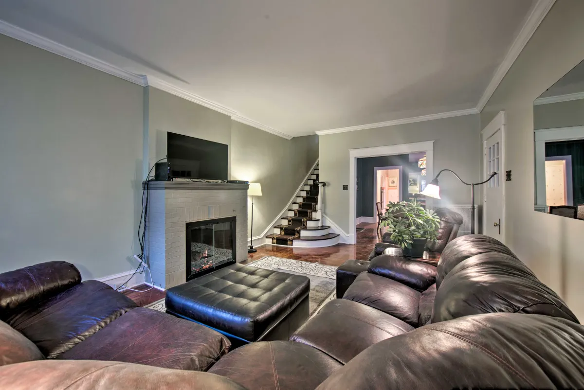 A living room with a couch , ottoman , fireplace and television.