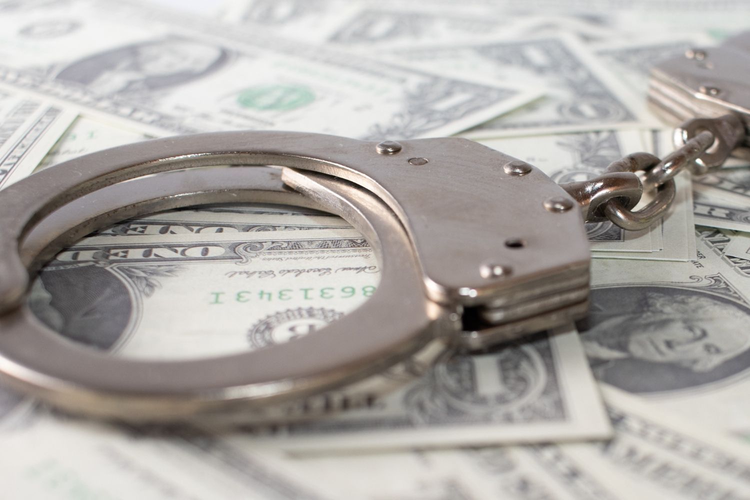 Handcuffs on top of a pile of US dollar bills. White Collar Crimes Law Attorney in Nashville, Tennessee