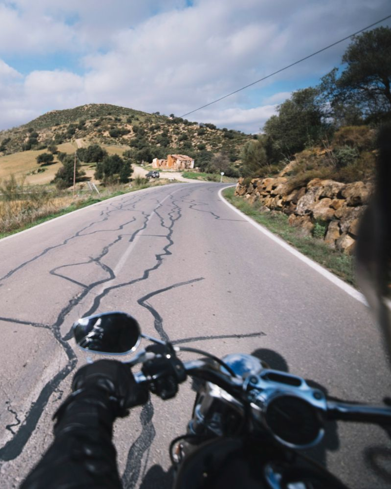 Motorcycle rider on a winding road with cracked pavement. Motorcycle Accidents Law Attorney in Nashville, Tennessee