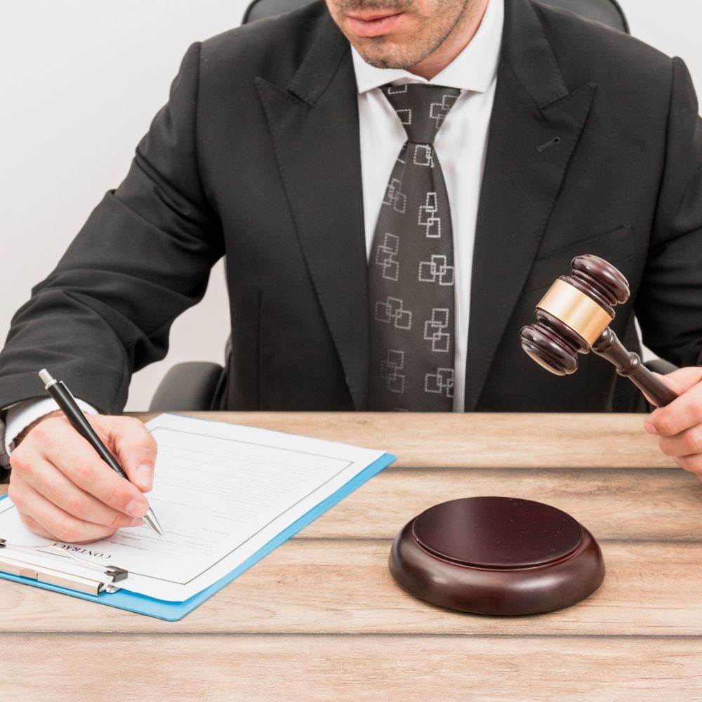 Man in suit writing, holding gavel. Desk with legal pad and sound block. Boundary Disputes Law Attorney in Nashville, Tennessee