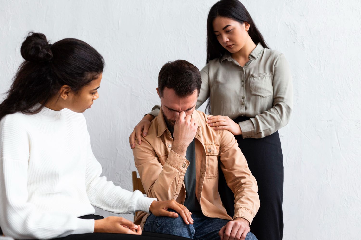 Two women comfort a person seated in a chair, all with concerned expressions. Tennessee Vulnerable Persons Abuse Registry Law Attorney in Nashville, Tennessee
